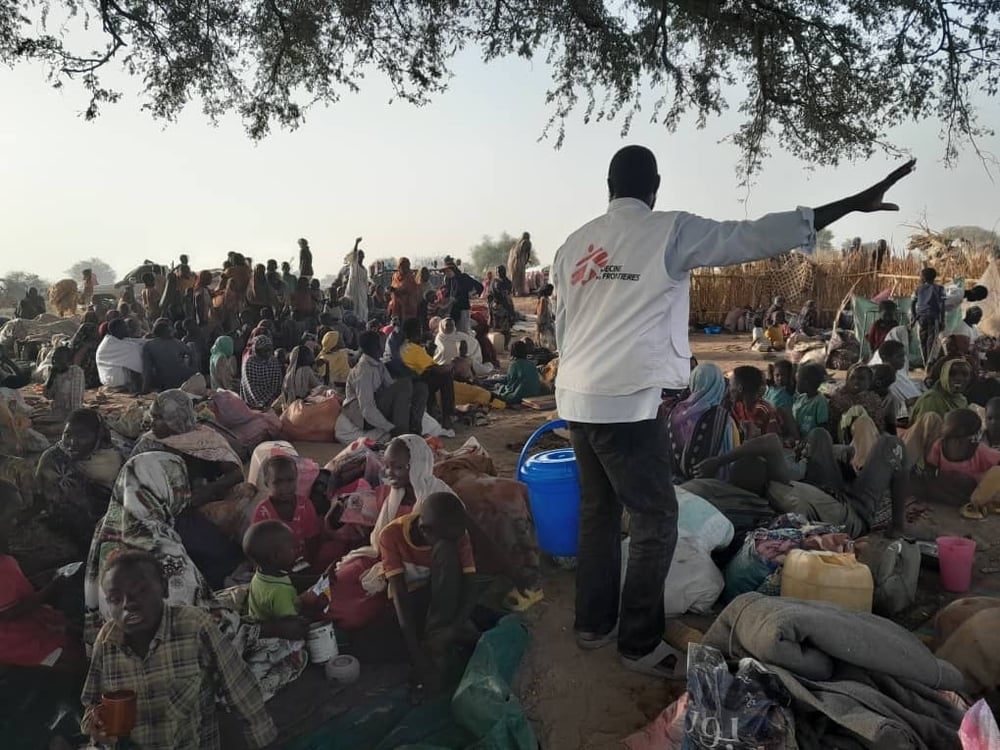 Trabajador de Médicos Sin Fronteras (MSF) dirigiendo a una multitud de personas refugiadas y desplazadas por la crisis humanitaria en Sudán.